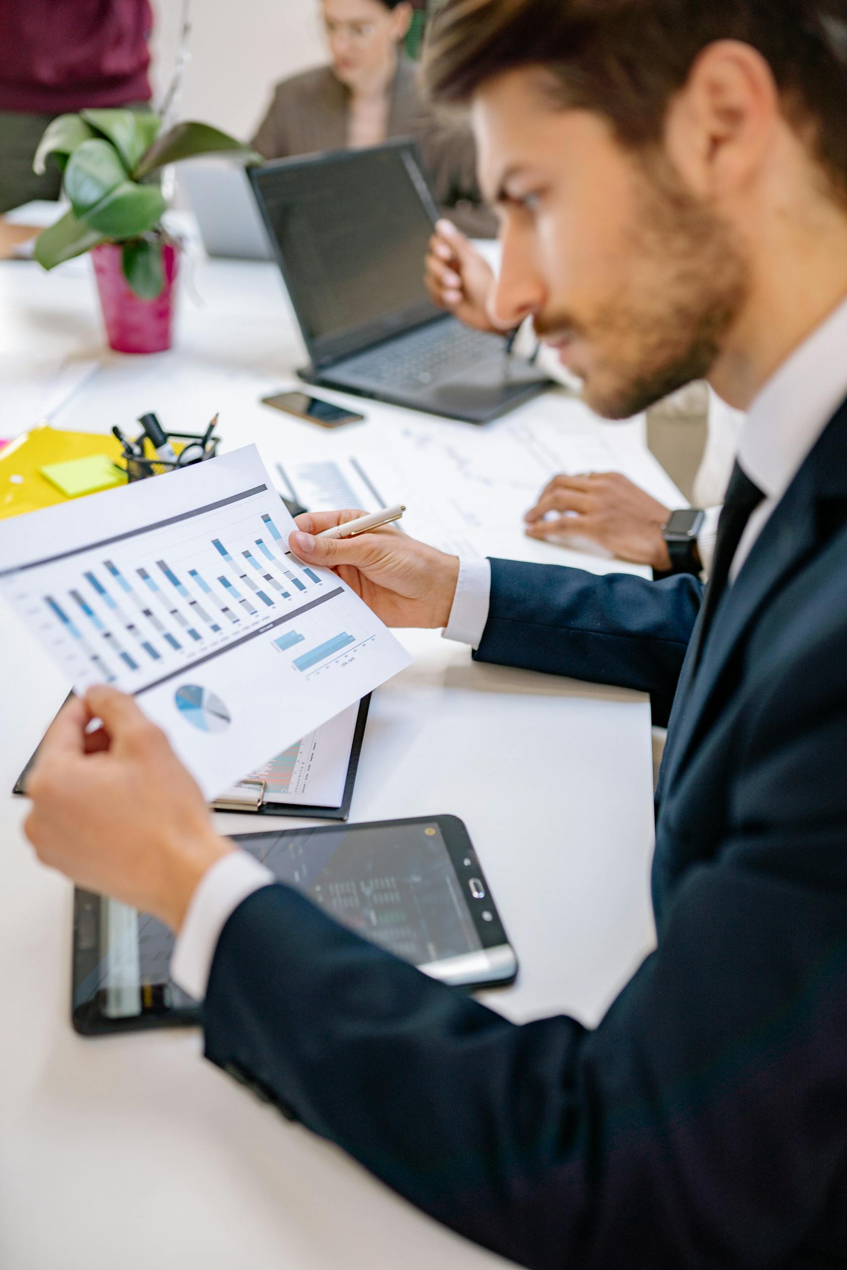 Focused businessman reviewing graphs and charts during a meeting in a modern office.